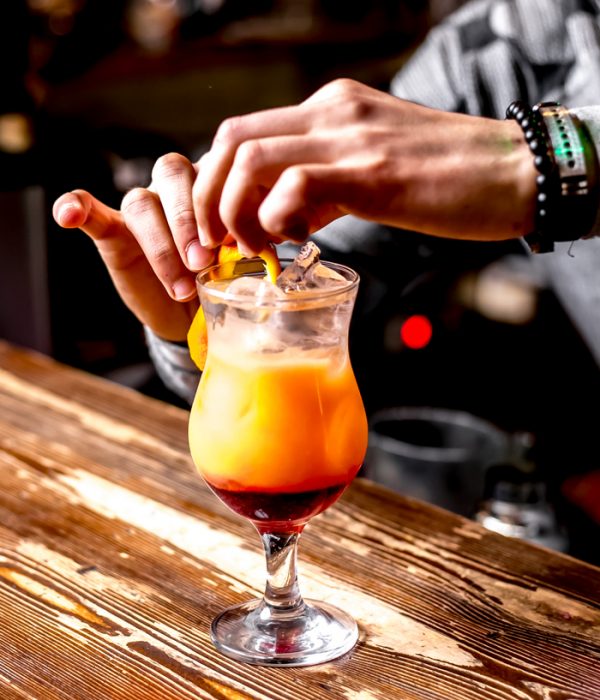 side view the bartender makes an orange peel decor cocktail
